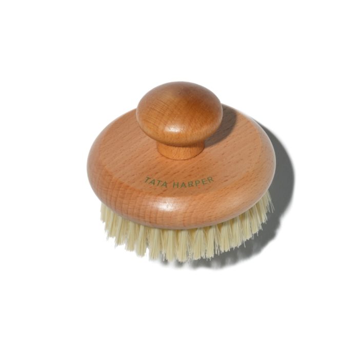 A handheld body brush with a wooden knob and short bristles